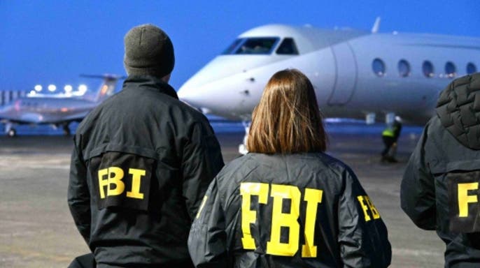 เจ้าหน้าที่ FBI ยืนอยู่บนลานบินขณะเครื่องบินขนส่งตัว โซไบดูล อามิน มาถึง