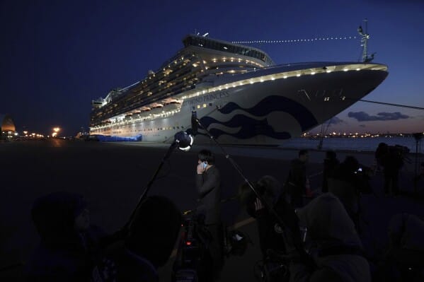 นักข่าวทำงานใกล้กับเรือสำราญ Diamond Princess ที่ถูกกักตัวอยู่ที่ท่าเรือโยโกฮาม่า เมื่อวันที่ 10 กุมภาพันธ์ 2020 ที่เมืองโยโกฮาม่า ประเทศญี่ปุ่น (ภาพ AP/Eugene Hoshiko, แฟ้มภาพ)
