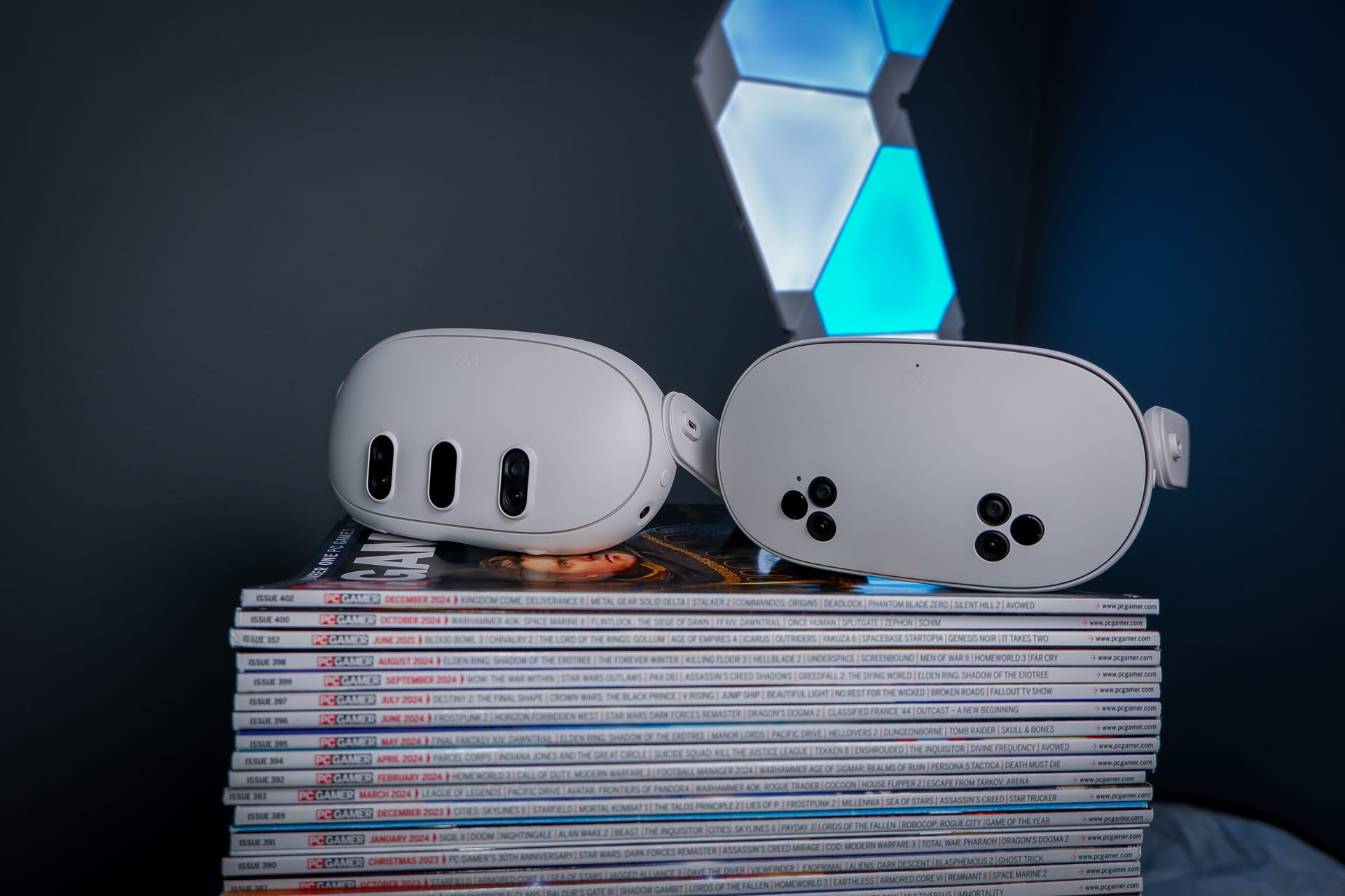 เฮดเซ็ต Meta Quest 3S วางคู่กับ Quest 3 และ Quest 2 บนกองนิตยสาร PC Gamer
