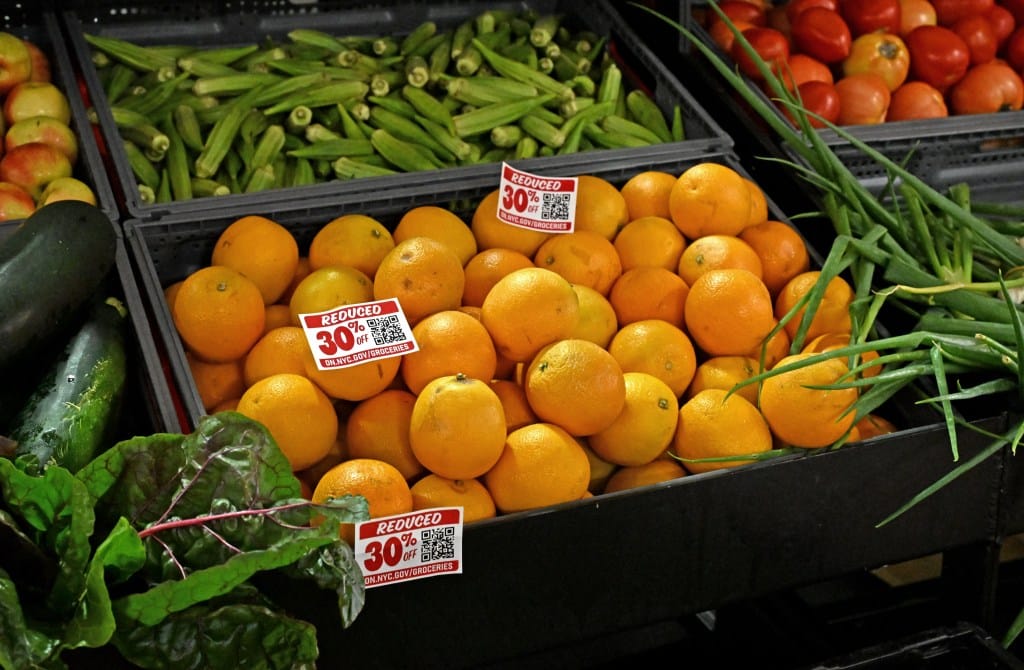 Produce, including oranges, okra, and tomatoes, on display with 