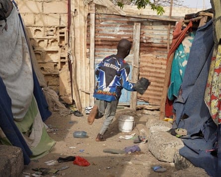 A boy running in an alley between shacks
