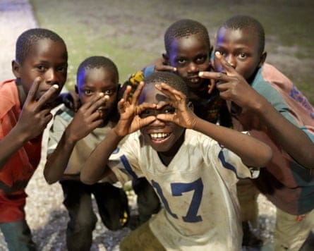 Five boys pose for the camera, holding their fingers up in what may be intended as gang hand signs