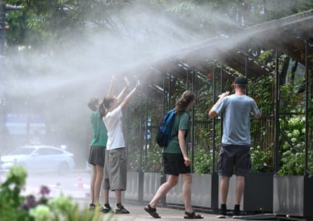 People stand in a mist-spraying zone to cool off on a street in Seoul