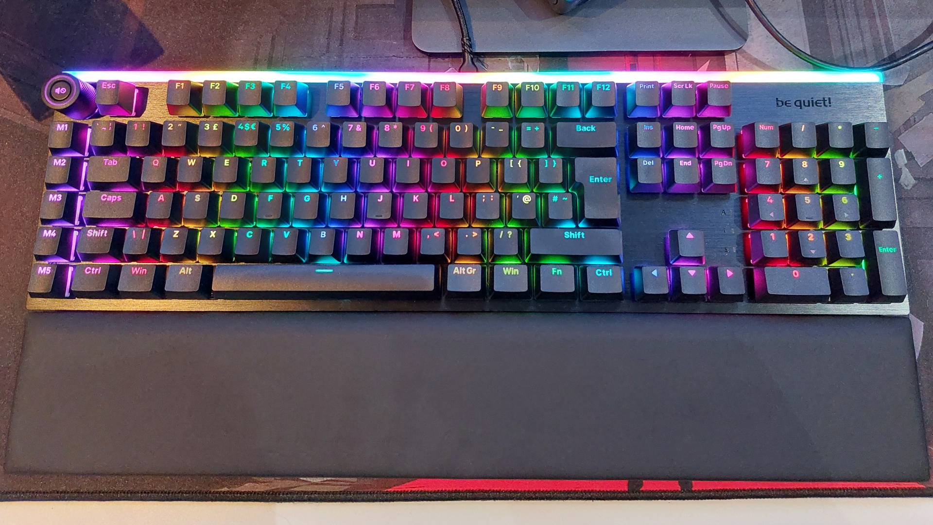 Be Quiet's Light Mount mechanical gaming keyboard sits on a large red and black mouse mat with vibrant rainbow RGB lighting