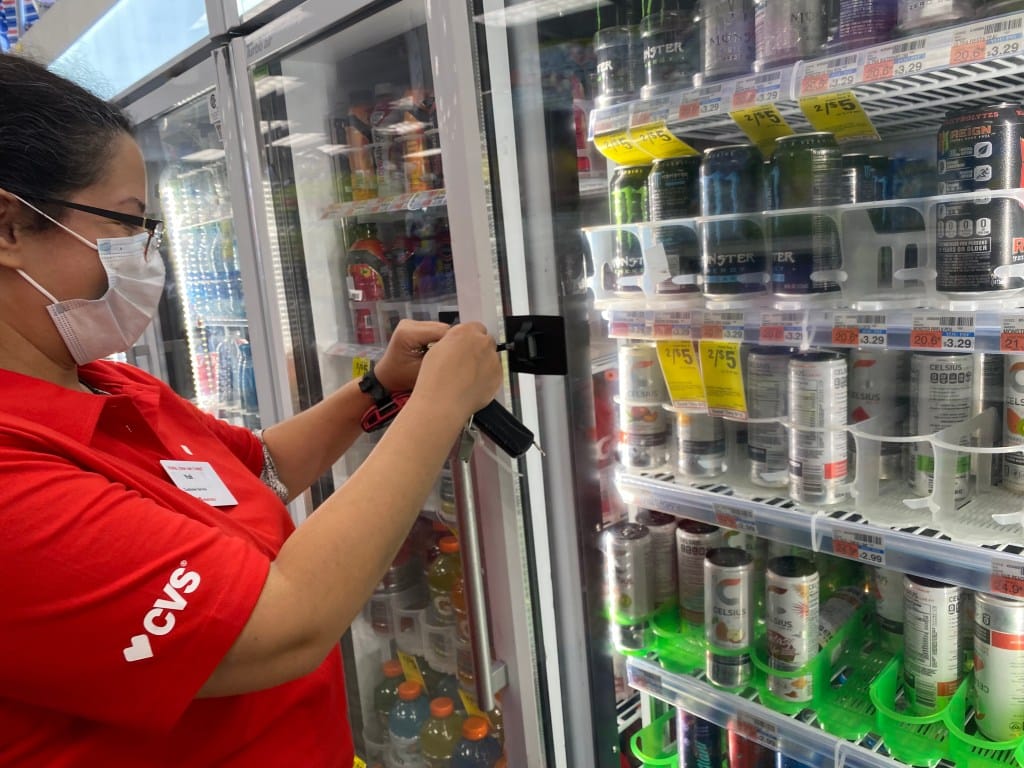 พนักงาน CVS Pharmacy ไขกุญแจตู้เย็นเพื่อหยิบเครื่องดื่มชูกำลังให้ลูกค้า