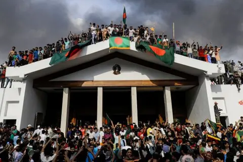 Getty Images ผู้ประท้วงต่อต้านรัฐบาลถือธงชาติบังกลาเทศขณะบุกเข้าไปในทำเนียบของนายกรัฐมนตรีชีค ฮาซินา ที่กรุงธากา เมื่อวันที่ 5 สิงหาคม 2024