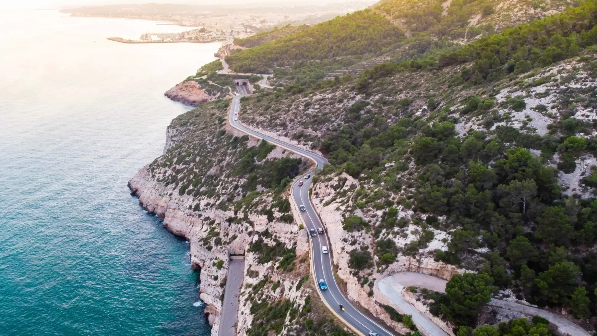 A road curves between the cliffs overlooking the sea near Garraf Beach