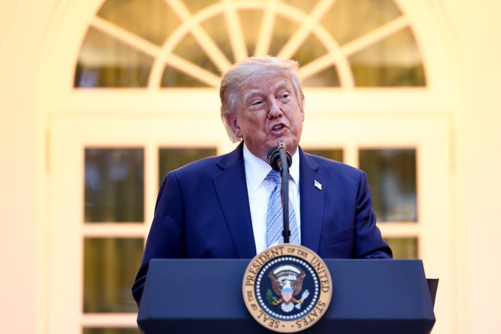 Donald Trump speaks from behind a podium with the Seal of the President of the United States.