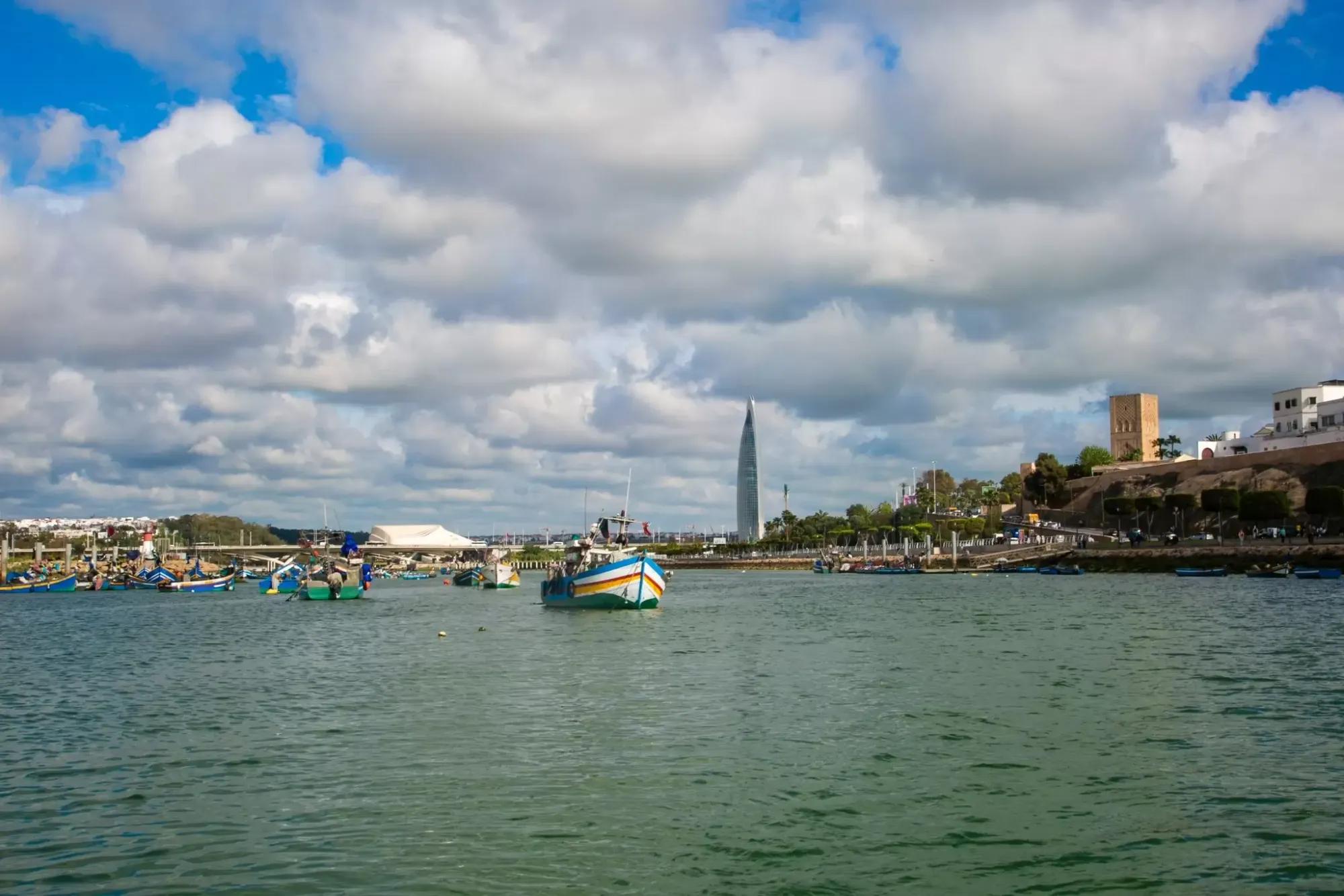 เรือในน้ำ มีหอคอยสูงอยู่ริมฝั่งด้านขวาในระยะไกล