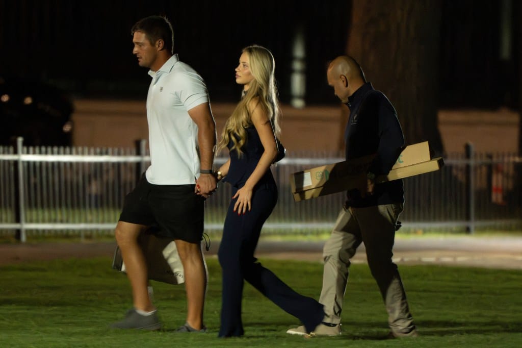 Bryson DeChambeau and Mikayla Demaiter walking towards a vehicle with an aide.
